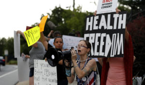 Anti vaccine activist Erika Geuser protests outside the Center of Disease Control and Prevention after a vaccine meeting Wednesday, June 26, 2019, in Atlanta. (AP Photo/John Bazemore)