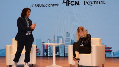 Finnish journalist Jessikka Aro (right) reacts to a standing ovation from the crowd of fact-checkers at GlobalFact 10 in Seoul, South Korea, after she talked about the personal attacks she faced while investigating Russian internet trolling operations. At left is moderator Alanna Dvorak, international training manager for the International Fact-Checking Network.